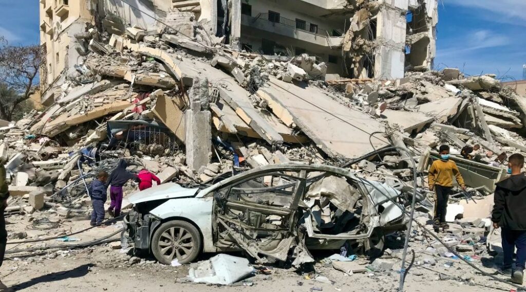 Un cotxe destrossat i un edifici ensorrat pels atacs israelians contra Gaza.